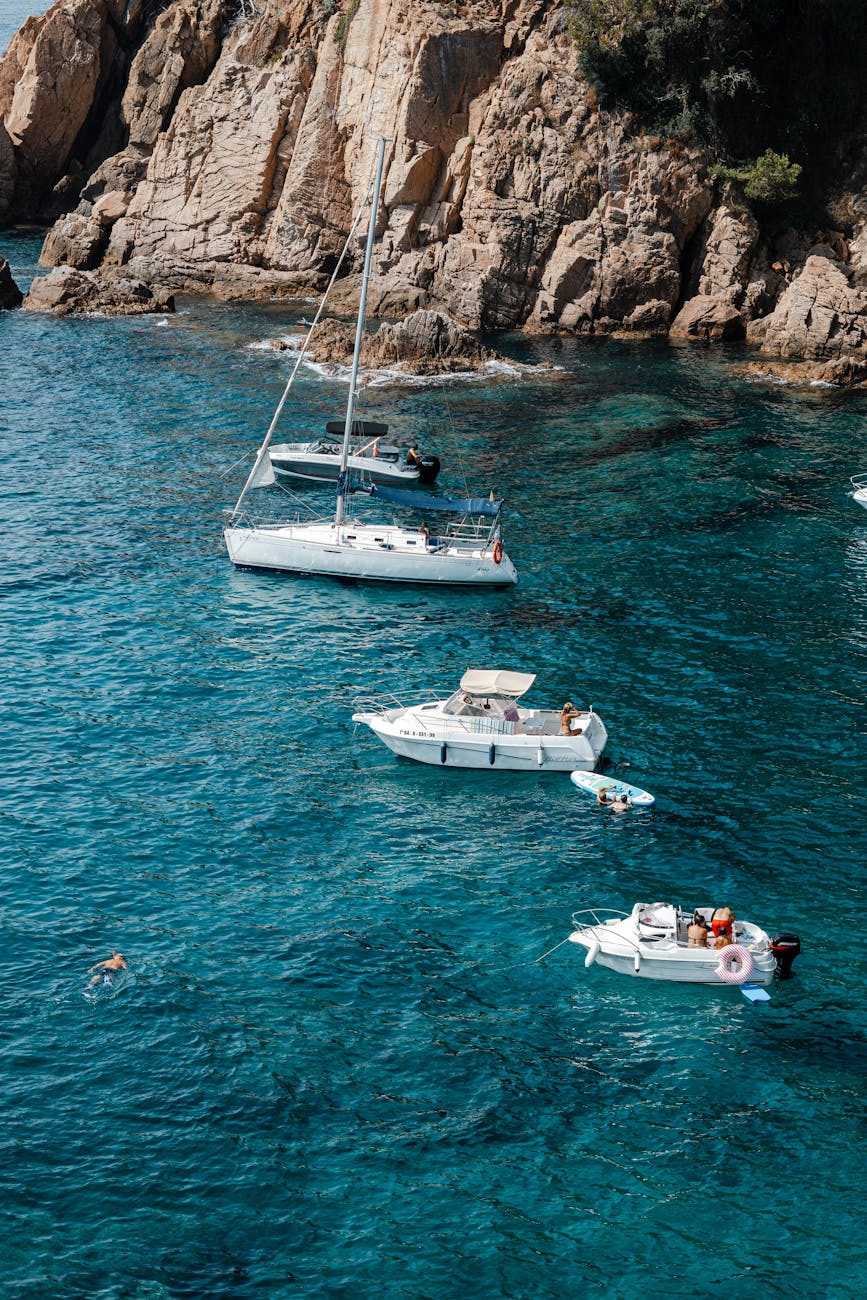 boats sailing in turquoise water near a cliff
